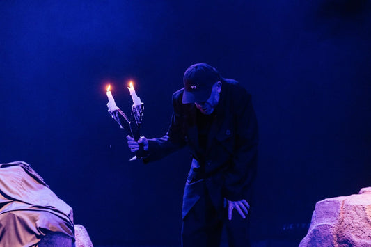Marius Kurkinski holding a candelabra on stage during The Cage of Theatre